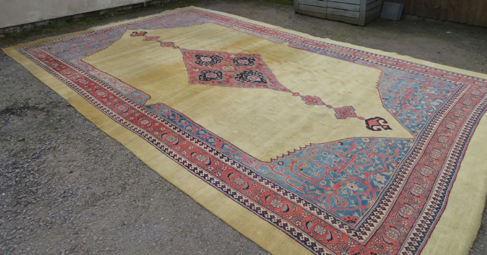 A large hand-knotted antique Persian Bidjar carpet featuring a gold yellow field, central diamond medallion, blue corner spandrels, and a patterned red border. View II