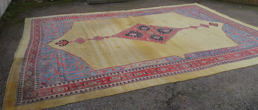 A large hand-knotted antique Persian Bidjar carpet featuring a gold yellow field, central diamond medallion, blue corner spandrels, and a patterned red border. View III