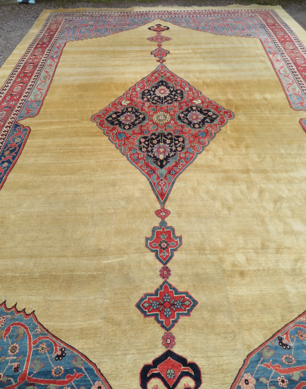 A large hand-knotted antique Persian Bidjar carpet featuring a gold yellow field, central diamond medallion, blue corner spandrels, and a patterned red border. View IV