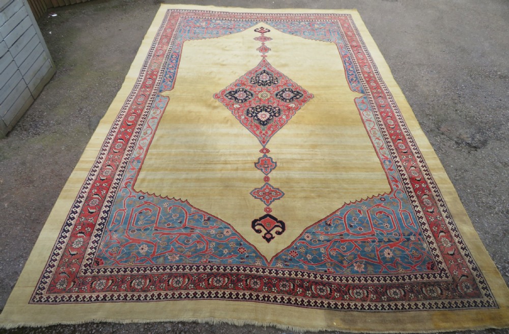 A large hand-knotted antique Persian Bidjar carpet featuring a gold yellow field, central diamond medallion, blue corner spandrels, and a patterned red border. View V
