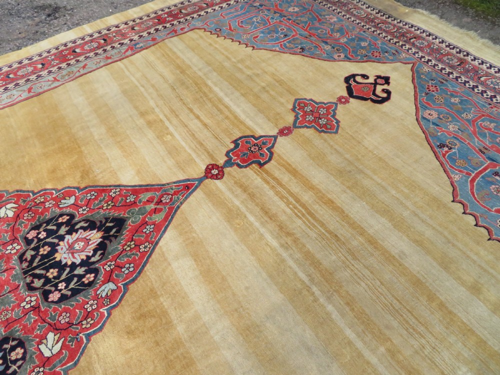 A large hand-knotted antique Persian Bidjar carpet featuring a gold yellow field, central diamond medallion, blue corner spandrels, and a patterned red border. View XVII