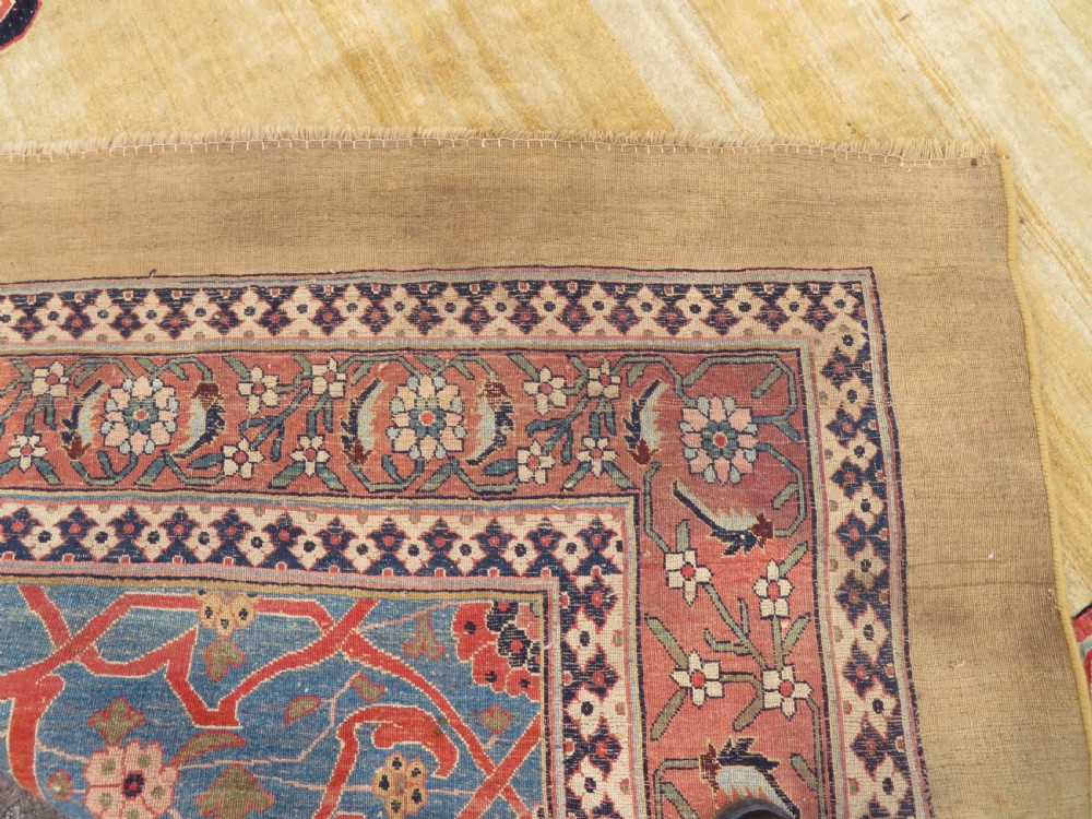 A large hand-knotted antique Persian Bidjar carpet featuring a gold yellow field, central diamond medallion, blue corner spandrels, and a patterned red border. View XX