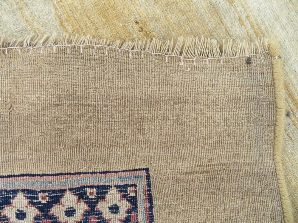 A large hand-knotted antique Persian Bidjar carpet featuring a gold yellow field, central diamond medallion, blue corner spandrels, and a patterned red border. View XXI
