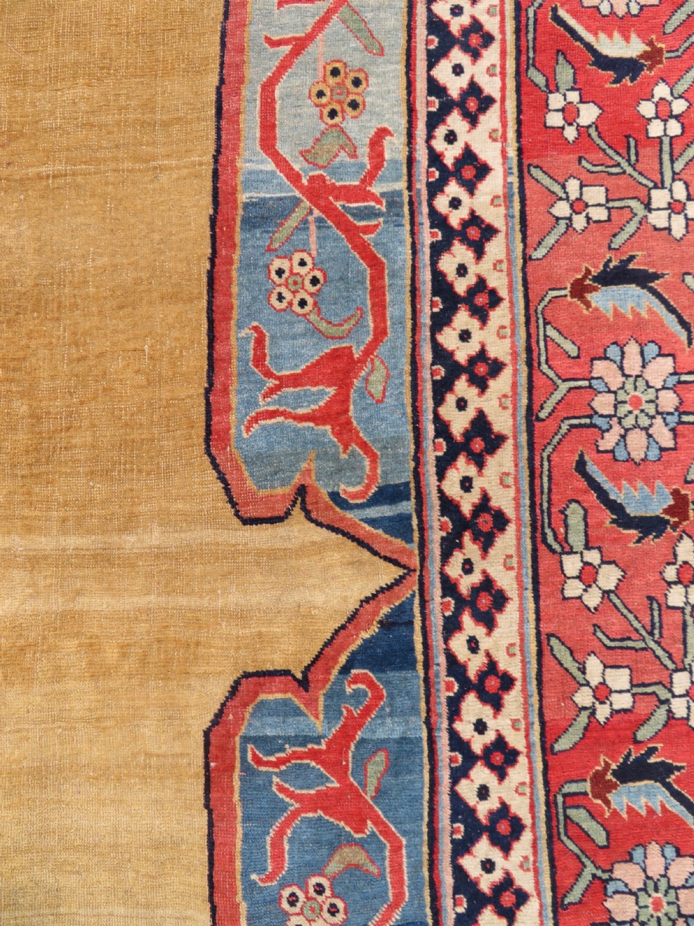 A large hand-knotted antique Persian Bidjar carpet featuring a gold yellow field, central diamond medallion, blue corner spandrels, and a patterned red border. View XXIV