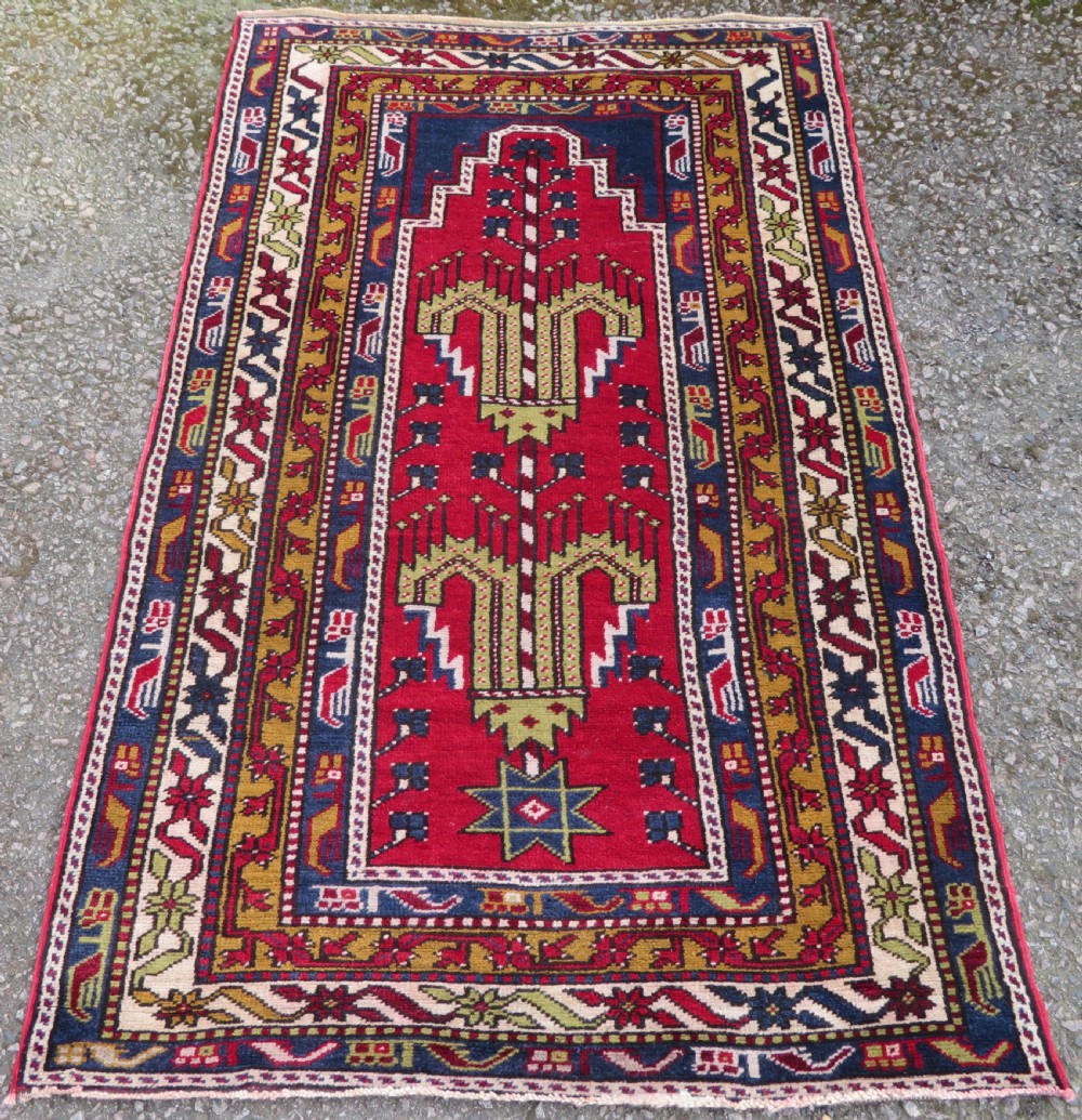 Hand-knotted Anatolian Kirsehir prayer rug featuring a red stepped niche central field with geometric floral motifs and a star, bordered by navy and mustard stripes.