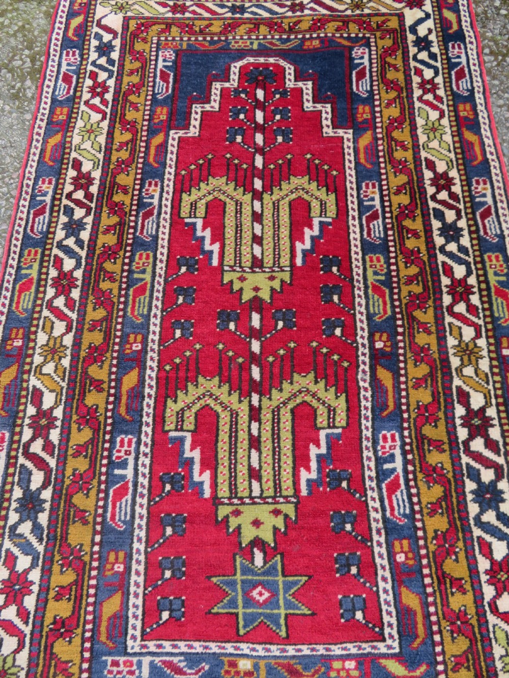 Hand-knotted Anatolian Kirsehir prayer rug featuring a red stepped niche central field with geometric floral motifs and a star, bordered by navy and mustard stripes. View III