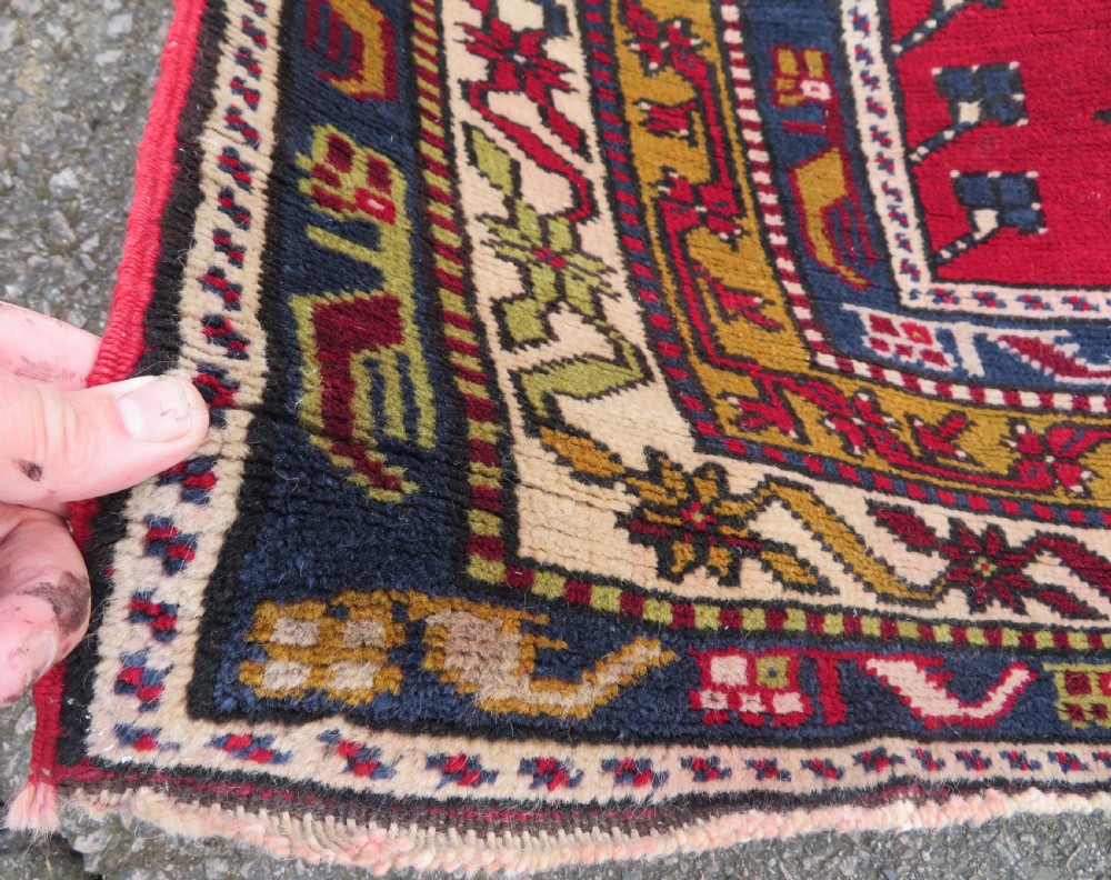 Hand-knotted Anatolian Kirsehir prayer rug featuring a red stepped niche central field with geometric floral motifs and a star, bordered by navy and mustard stripes. View IV