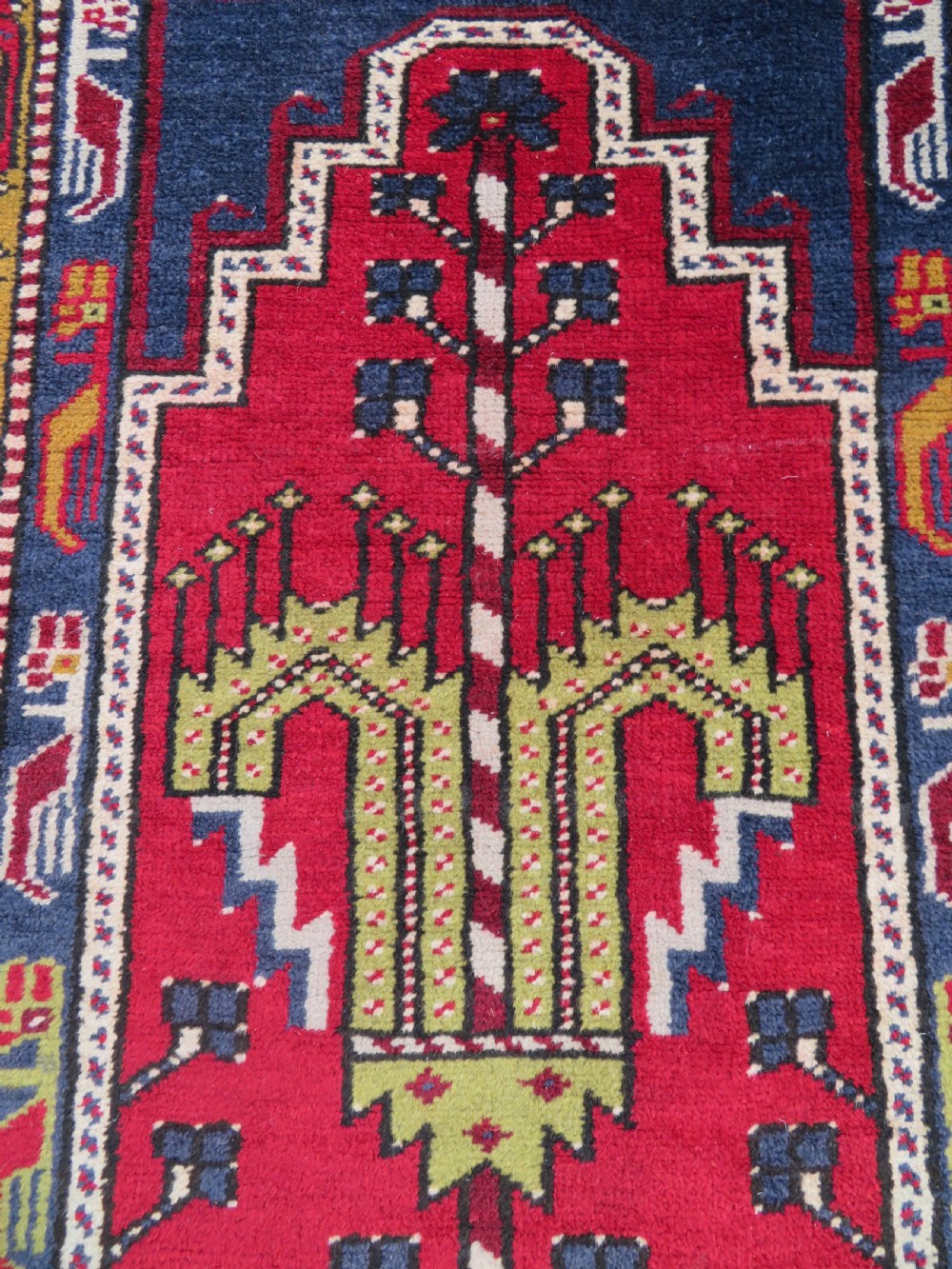 Hand-knotted Anatolian Kirsehir prayer rug featuring a red stepped niche central field with geometric floral motifs and a star, bordered by navy and mustard stripes. View VI