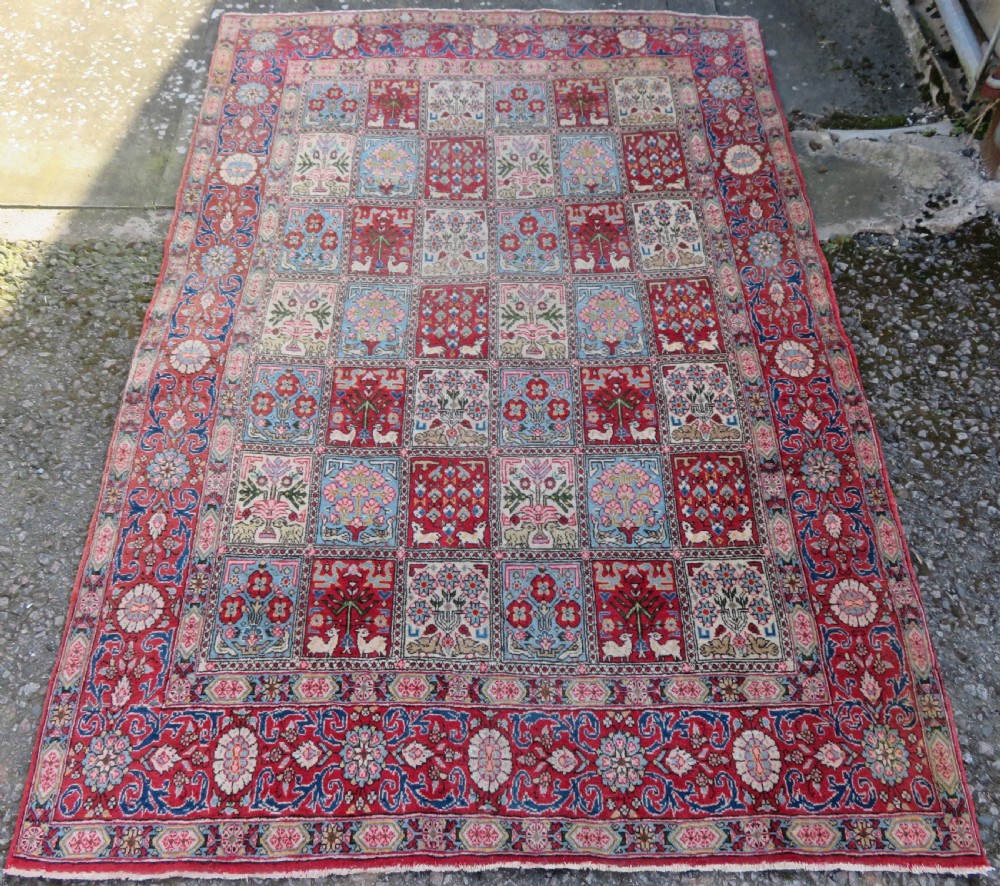 A hand-knotted Persian Qum rug featuring a grid tile pattern filled with floral and animal motifs inside a detailed red border.