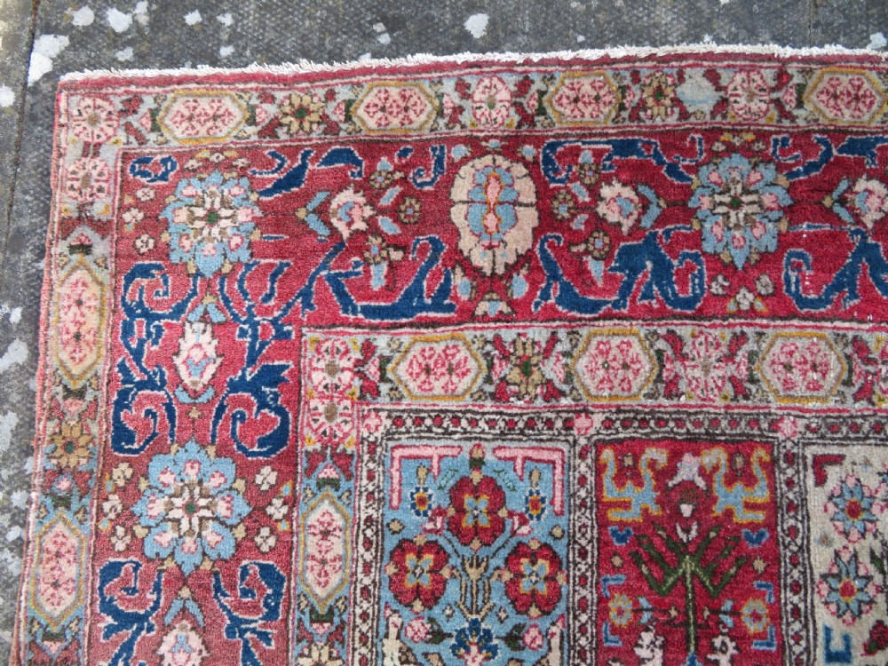 A hand-knotted Persian Qum rug featuring a grid tile pattern filled with floral and animal motifs inside a detailed red border. View VII