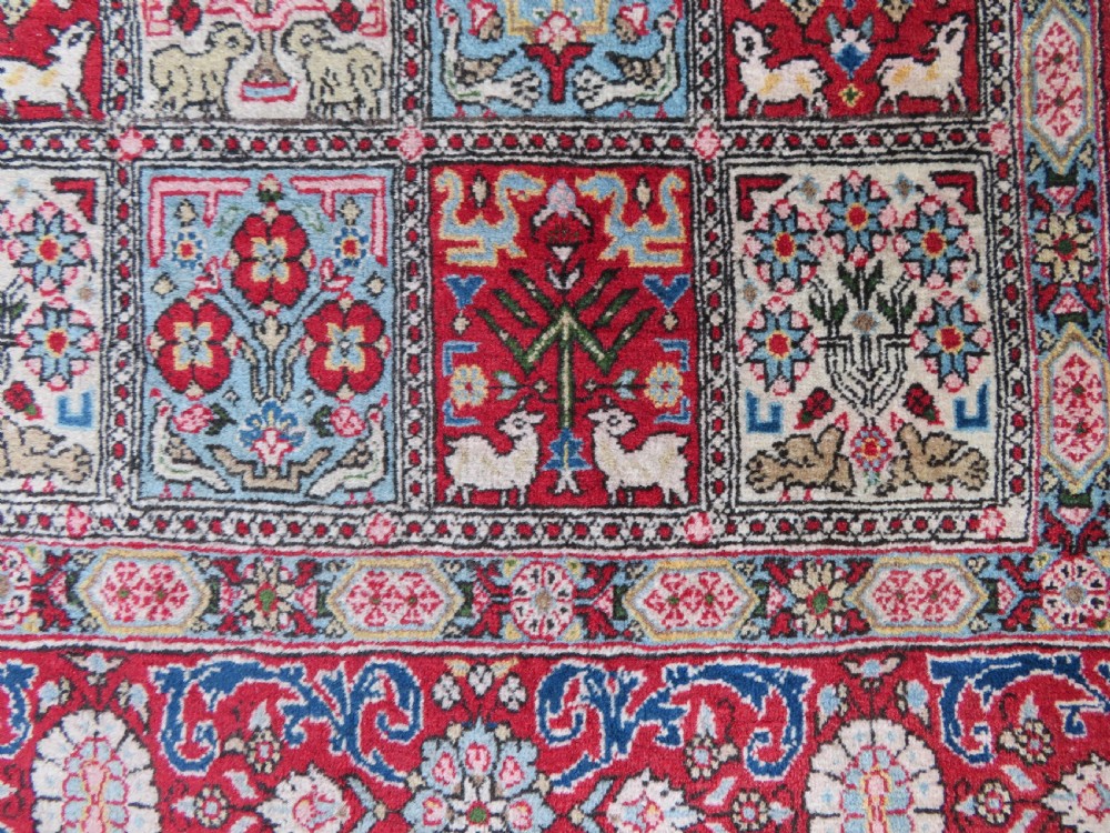 A hand-knotted Persian Qum rug featuring a grid tile pattern filled with floral and animal motifs inside a detailed red border. View X