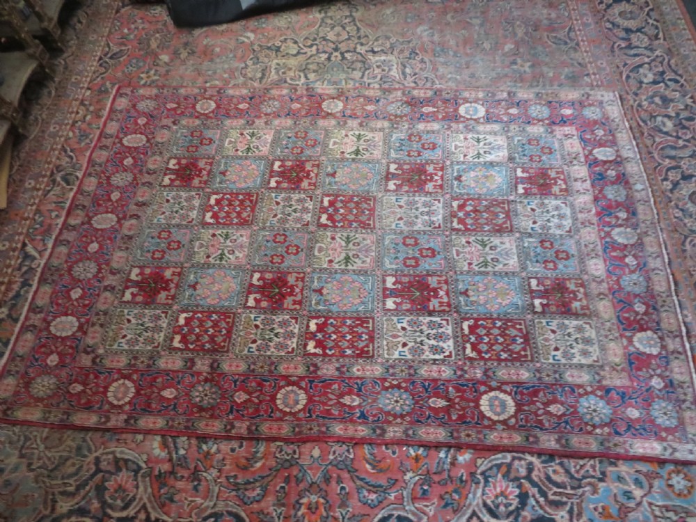 A hand-knotted Persian Qum rug featuring a grid tile pattern filled with floral and animal motifs inside a detailed red border. View XV