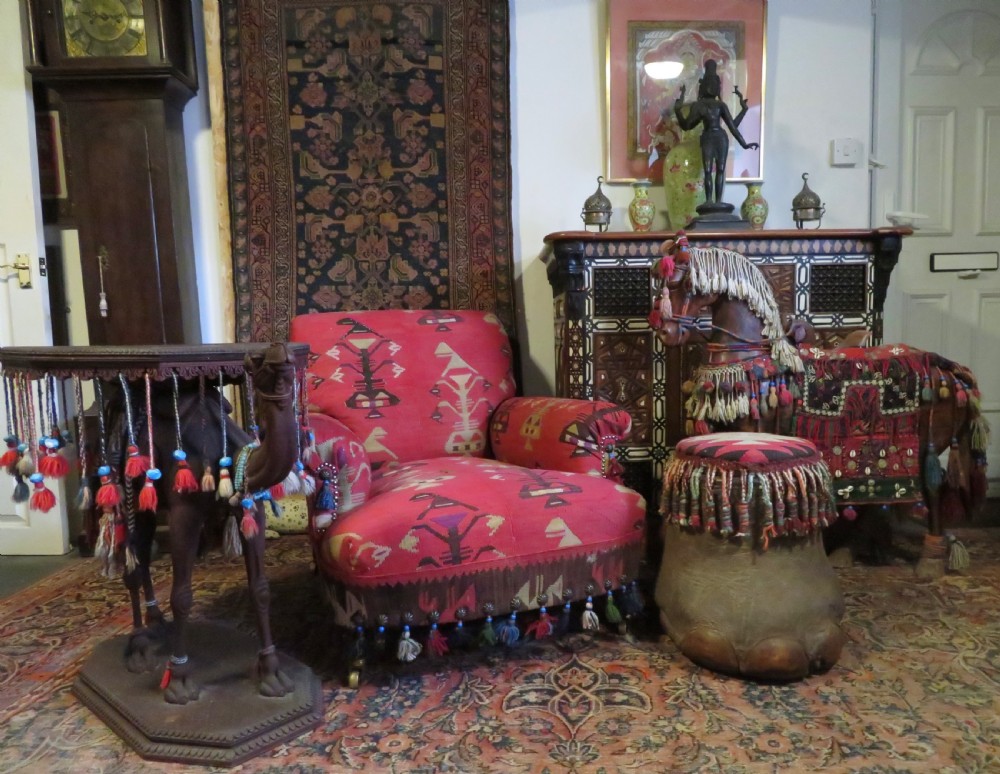 An antique low-slung club armchair upholstered in a geometric red wool kilim textile with turned legs and brass castors. View XIV