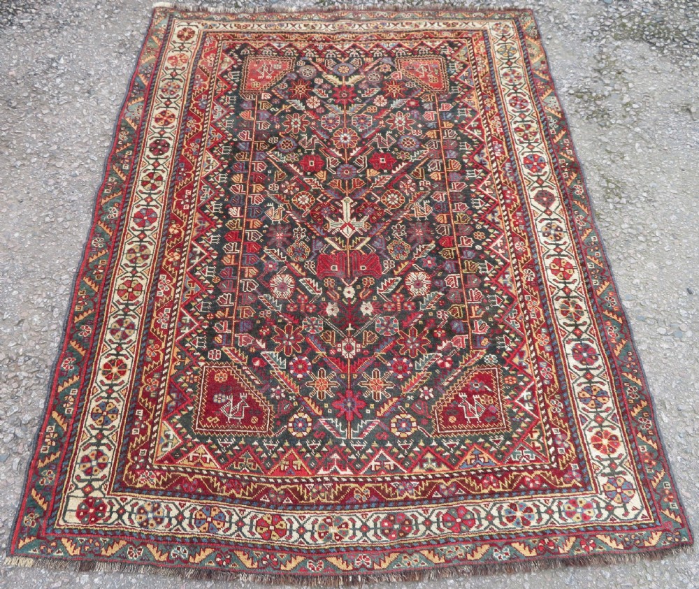 An antique hand-knotted Qashqai wool carpet with geometric bird, botanical motifs, and compound borders in deep red and navy blue.