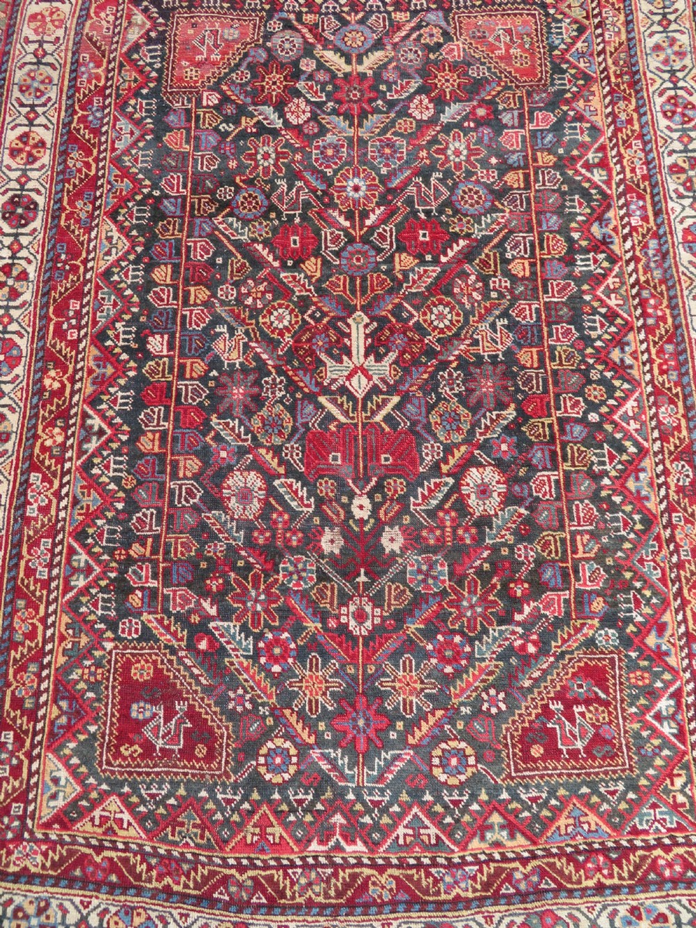 An antique hand-knotted Qashqai wool carpet with geometric bird, botanical motifs, and compound borders in deep red and navy blue. View IV