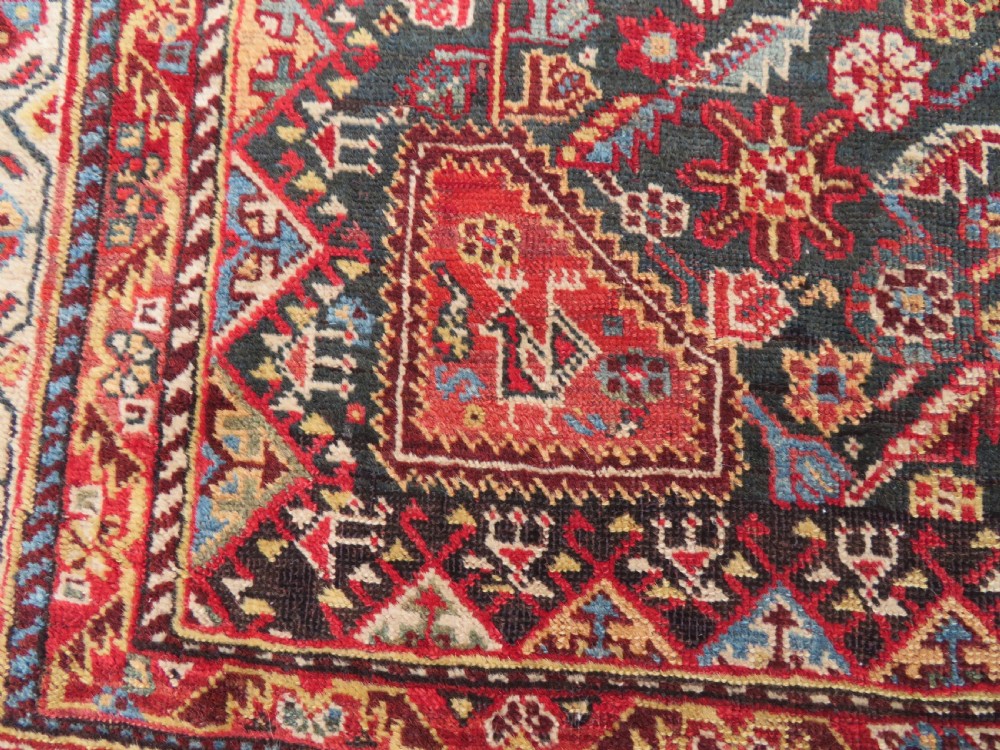 An antique hand-knotted Qashqai wool carpet with geometric bird, botanical motifs, and compound borders in deep red and navy blue. View X
