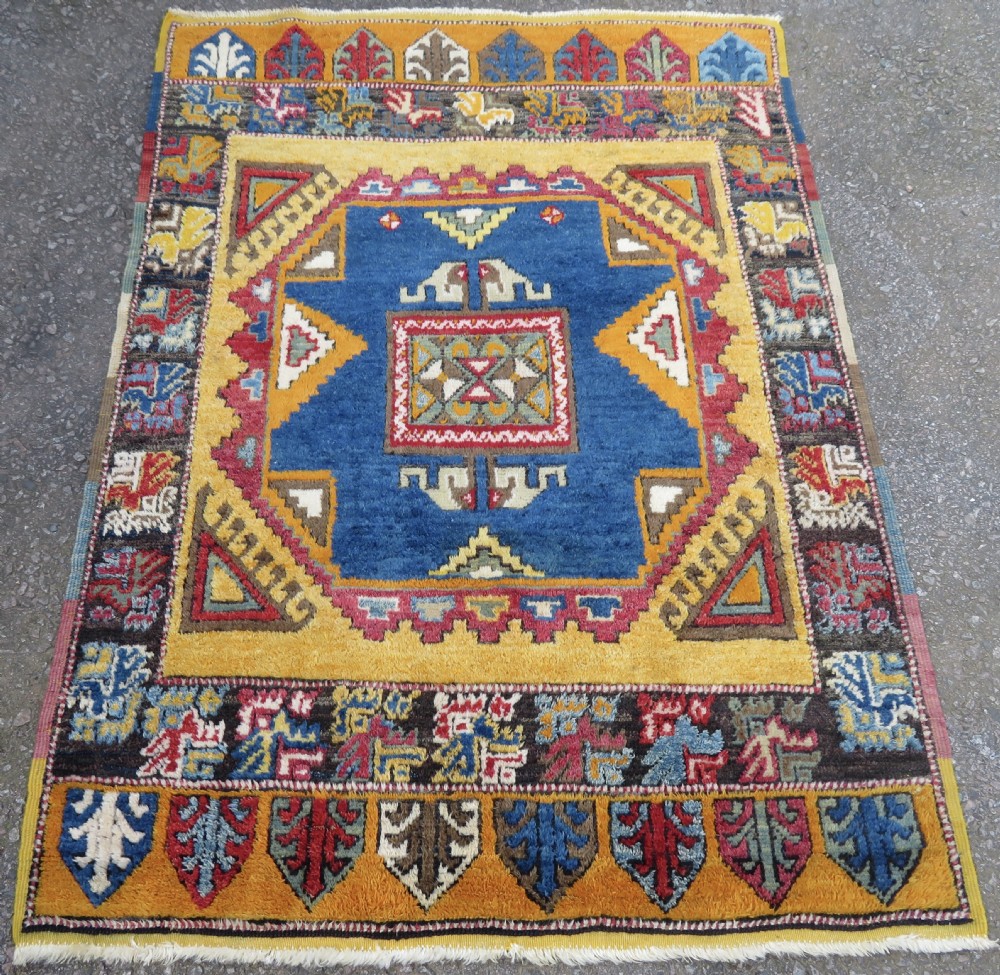 An antique Turkish Konya Yatak wool rug featuring a central indigo blue medallion surrounded by saffron yellow and geometric patterned borders. View II