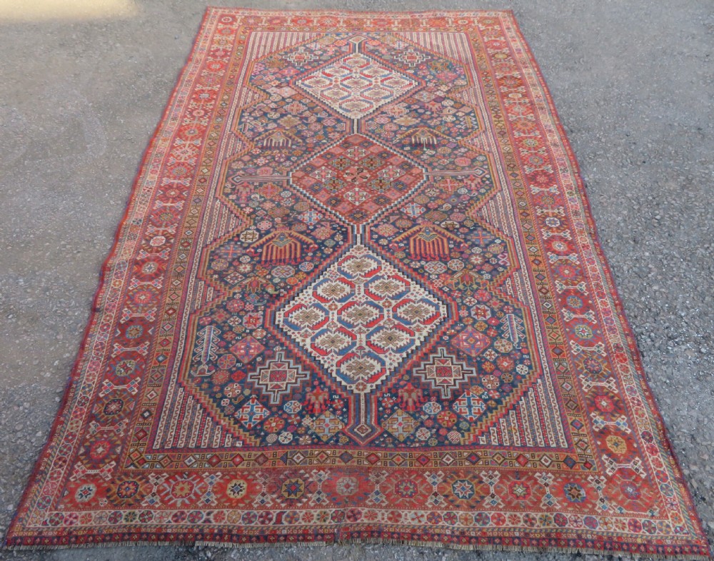 An antique hand-knotted Khamseh tribal carpet featuring multiple diamond medallions and geometric borders in navy blue, terracotta red, and cream wool. View II