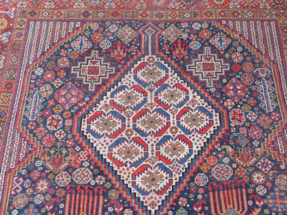 An antique hand-knotted Khamseh tribal carpet featuring multiple diamond medallions and geometric borders in navy blue, terracotta red, and cream wool. View VI