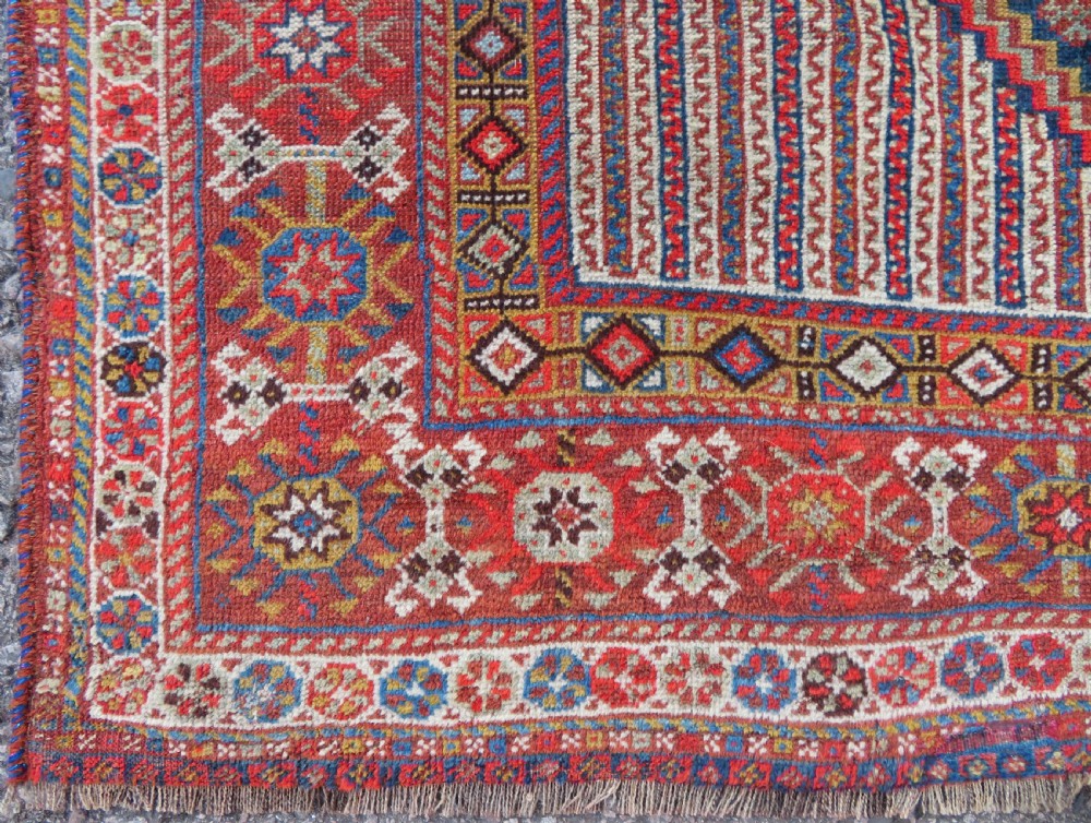An antique hand-knotted Khamseh tribal carpet featuring multiple diamond medallions and geometric borders in navy blue, terracotta red, and cream wool. View X