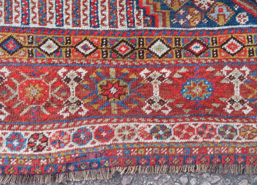 An antique hand-knotted Khamseh tribal carpet featuring multiple diamond medallions and geometric borders in navy blue, terracotta red, and cream wool. View XI