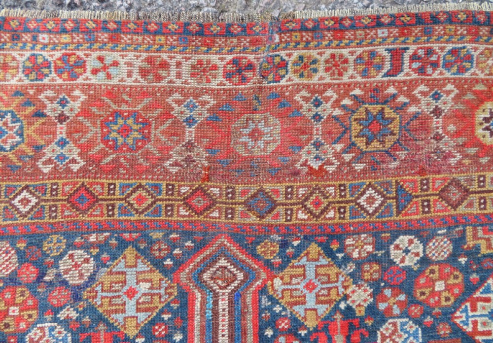 An antique hand-knotted Khamseh tribal carpet featuring multiple diamond medallions and geometric borders in navy blue, terracotta red, and cream wool. View XIV