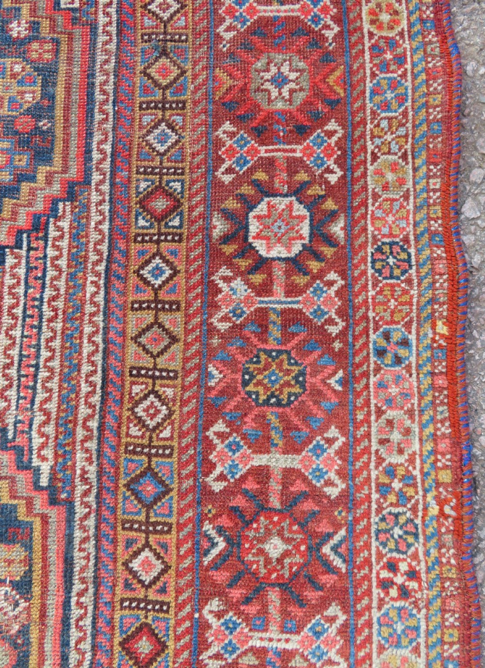 An antique hand-knotted Khamseh tribal carpet featuring multiple diamond medallions and geometric borders in navy blue, terracotta red, and cream wool. View XVI