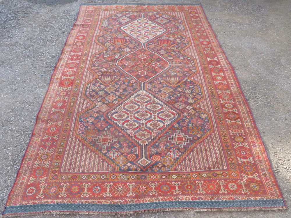 An antique hand-knotted Khamseh tribal carpet featuring multiple diamond medallions and geometric borders in navy blue, terracotta red, and cream wool. View XVIII