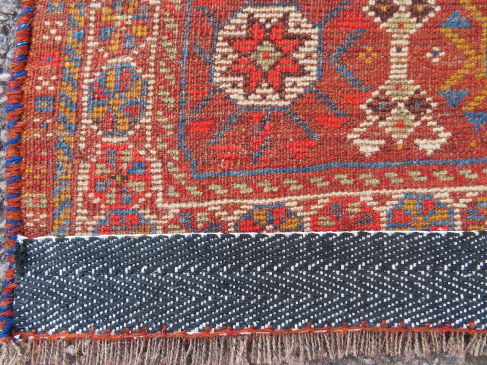 An antique hand-knotted Khamseh tribal carpet featuring multiple diamond medallions and geometric borders in navy blue, terracotta red, and cream wool. View XIX