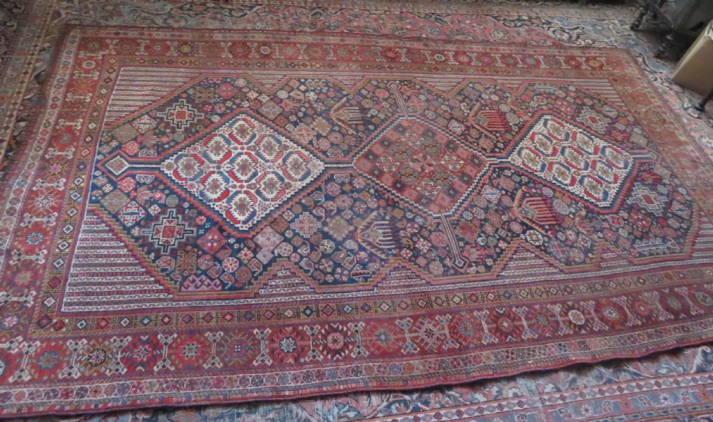 An antique hand-knotted Khamseh tribal carpet featuring multiple diamond medallions and geometric borders in navy blue, terracotta red, and cream wool. View XXIII