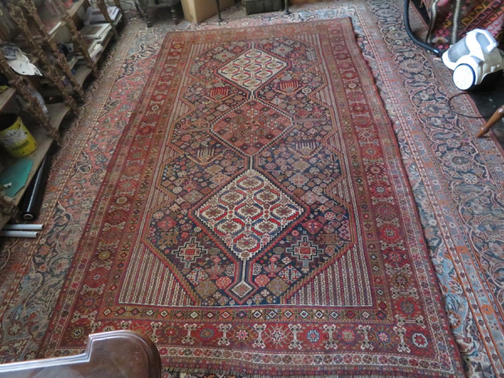 An antique hand-knotted Khamseh tribal carpet featuring multiple diamond medallions and geometric borders in navy blue, terracotta red, and cream wool. View XXIV