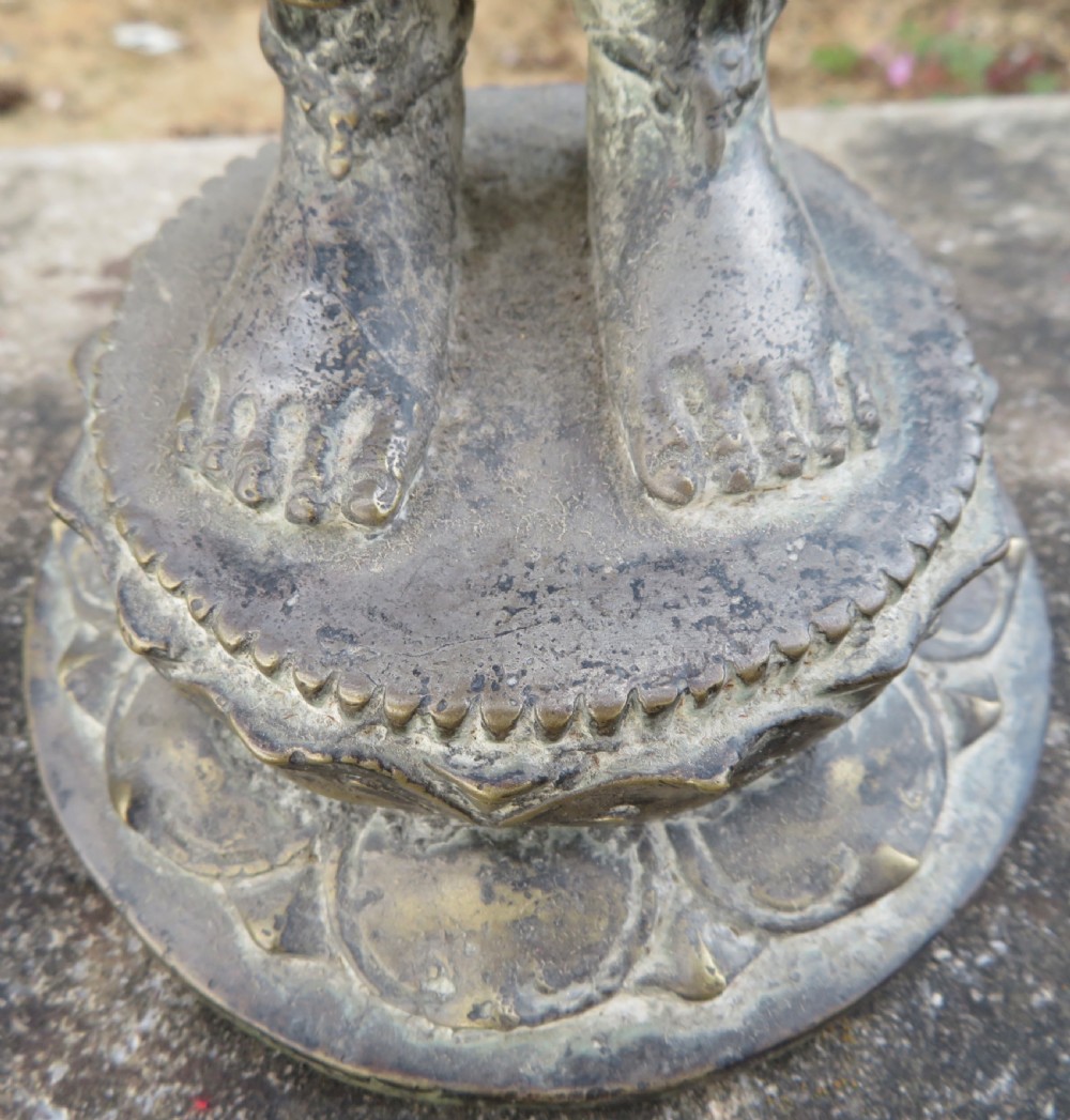 A standing four-armed copper alloy figure of the Hindu deity Shiva on a lotus pedestal with an aged patina. View VII