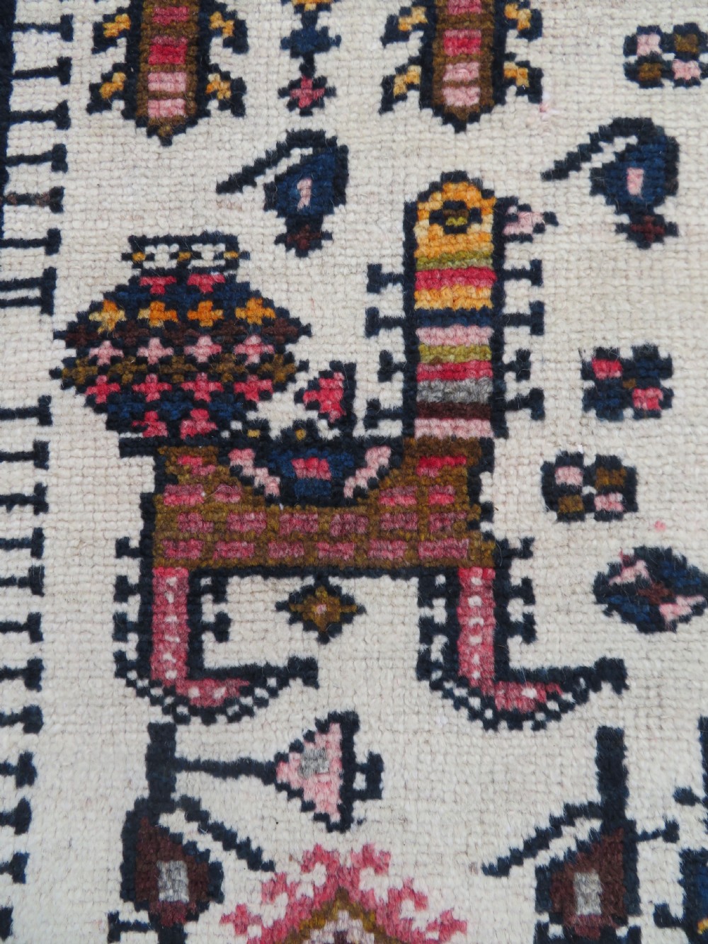 An antique hand-knotted Persian tribal rug featuring a geometric medallion and stylised animal figures in terracotta red, navy blue, and cream. View V