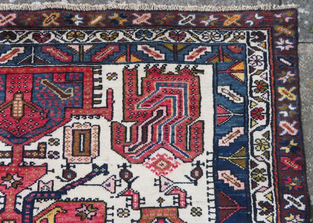 An antique hand-knotted Persian tribal rug featuring a geometric medallion and stylised animal figures in terracotta red, navy blue, and cream. View VIII
