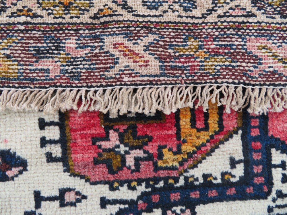 An antique hand-knotted Persian tribal rug featuring a geometric medallion and stylised animal figures in terracotta red, navy blue, and cream. View XIII