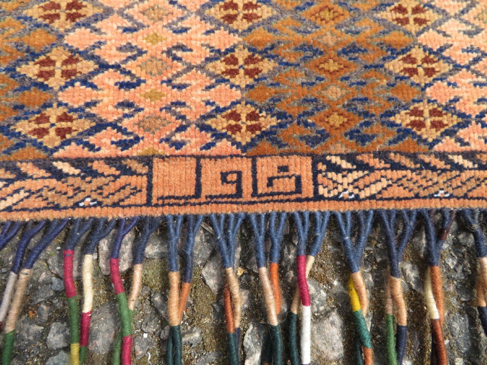 A handwoven arch-shaped Ersari kapunuk textile with geometric terracotta motifs and long decorative wool tassels dangling from the base. View II