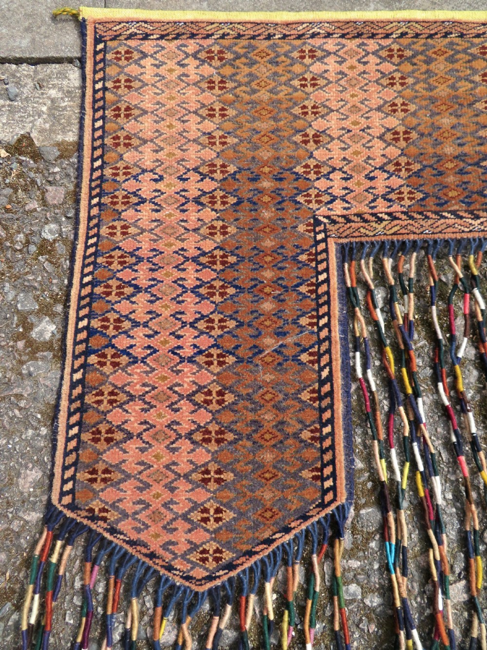 A handwoven arch-shaped Ersari kapunuk textile with geometric terracotta motifs and long decorative wool tassels dangling from the base. View IV