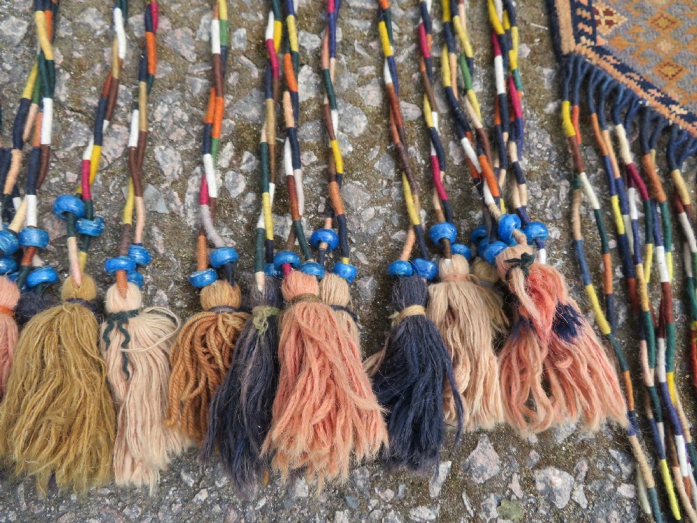 A handwoven arch-shaped Ersari kapunuk textile with geometric terracotta motifs and long decorative wool tassels dangling from the base. View VII