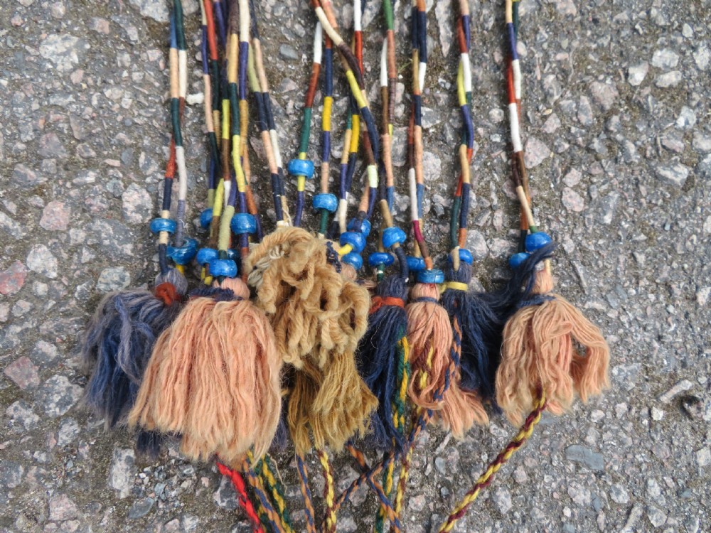 A handwoven arch-shaped Ersari kapunuk textile with geometric terracotta motifs and long decorative wool tassels dangling from the base. View VIII