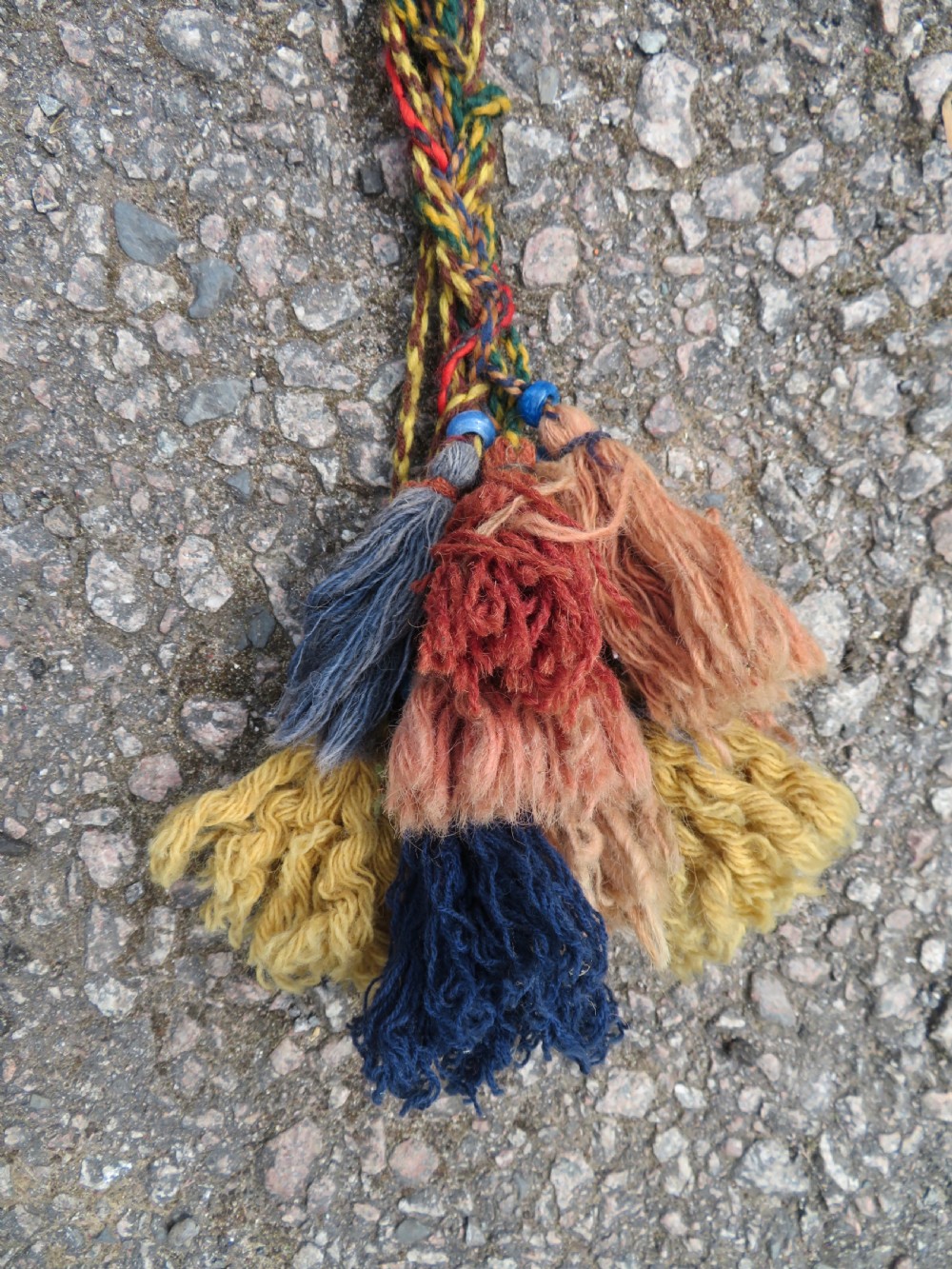 A handwoven arch-shaped Ersari kapunuk textile with geometric terracotta motifs and long decorative wool tassels dangling from the base. View IX