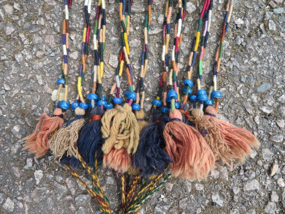 A handwoven arch-shaped Ersari kapunuk textile with geometric terracotta motifs and long decorative wool tassels dangling from the base. View XI