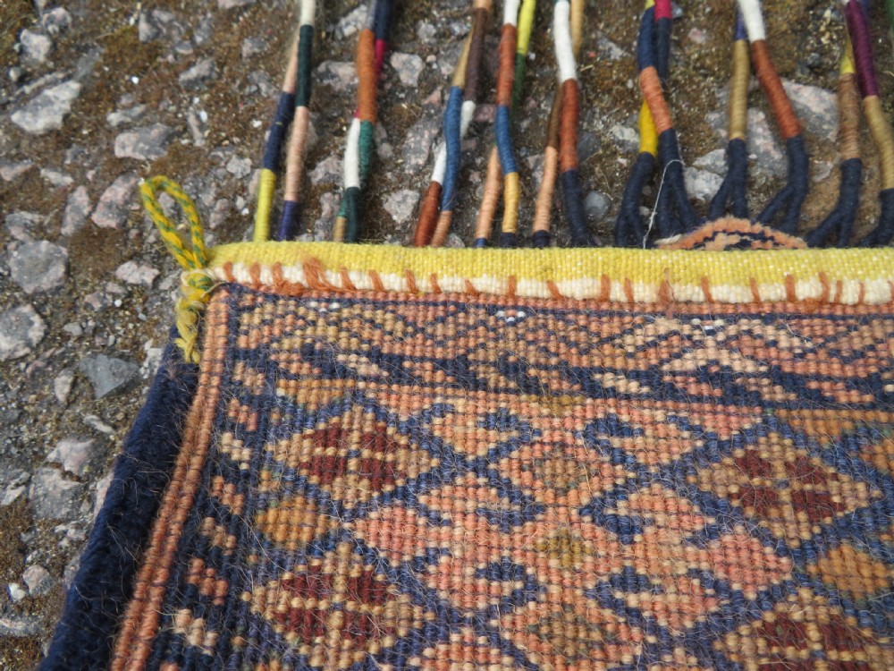 A handwoven arch-shaped Ersari kapunuk textile with geometric terracotta motifs and long decorative wool tassels dangling from the base. View XIV