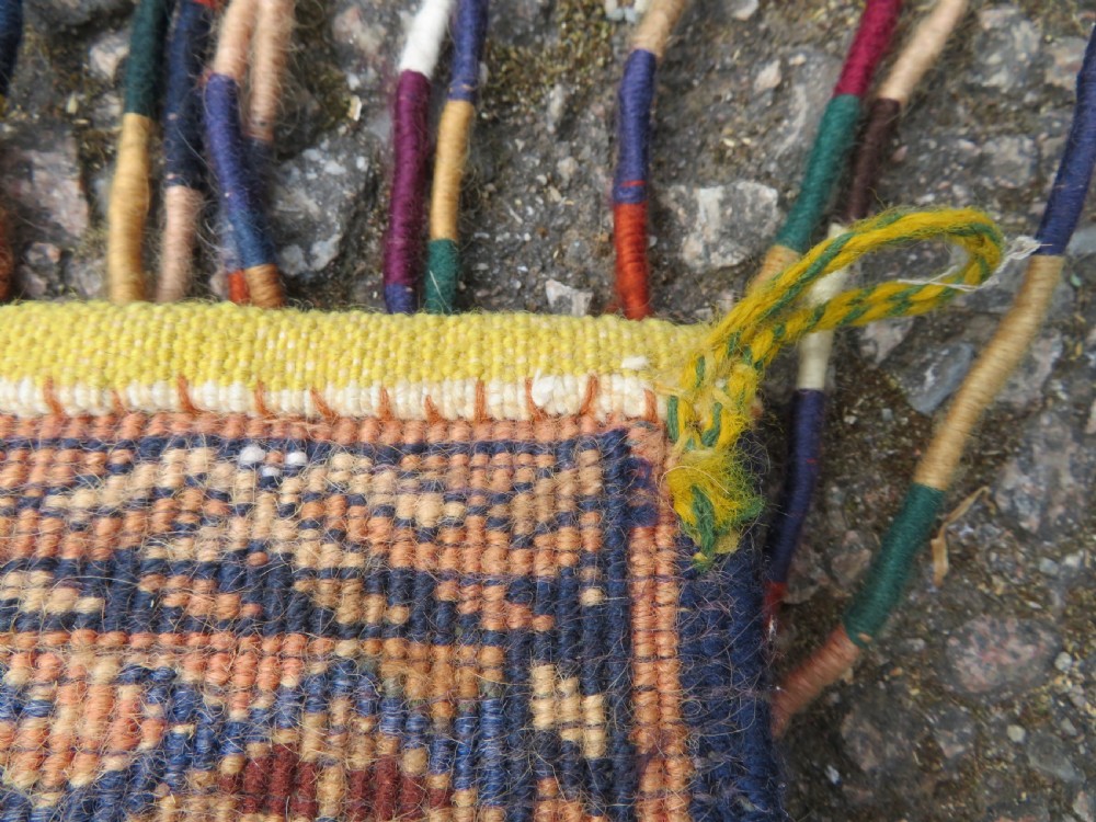 A handwoven arch-shaped Ersari kapunuk textile with geometric terracotta motifs and long decorative wool tassels dangling from the base. View XV