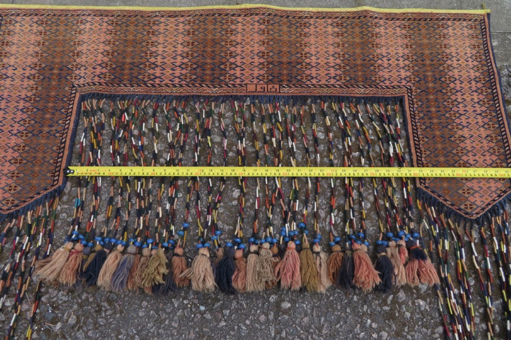 A handwoven arch-shaped Ersari kapunuk textile with geometric terracotta motifs and long decorative wool tassels dangling from the base. View XVI