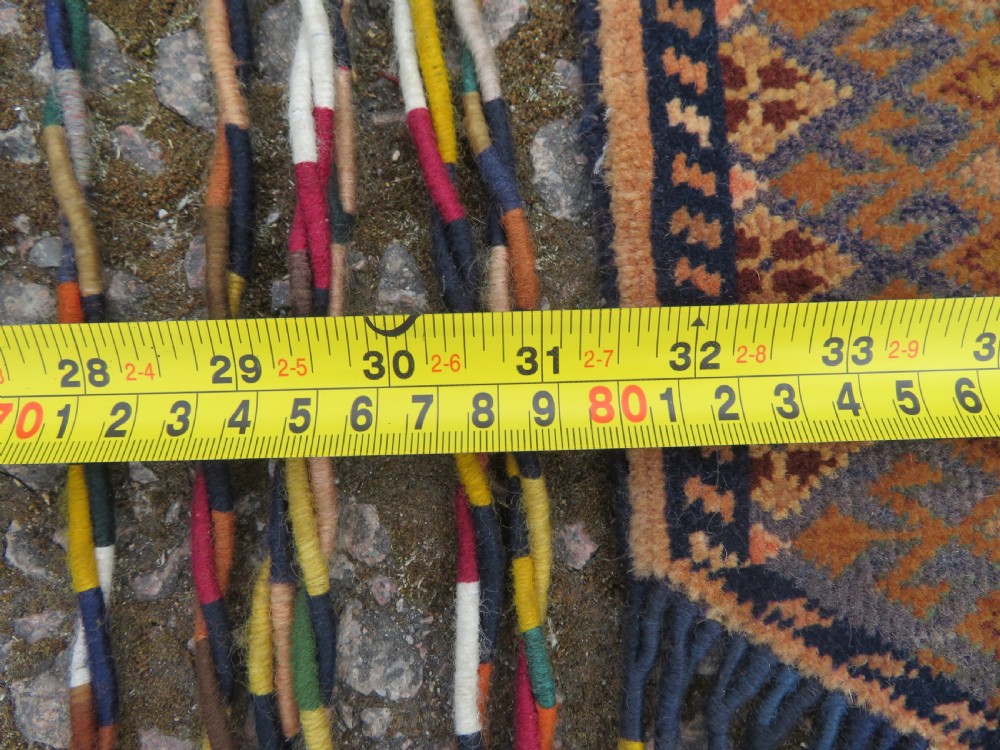 A handwoven arch-shaped Ersari kapunuk textile with geometric terracotta motifs and long decorative wool tassels dangling from the base. View XVII