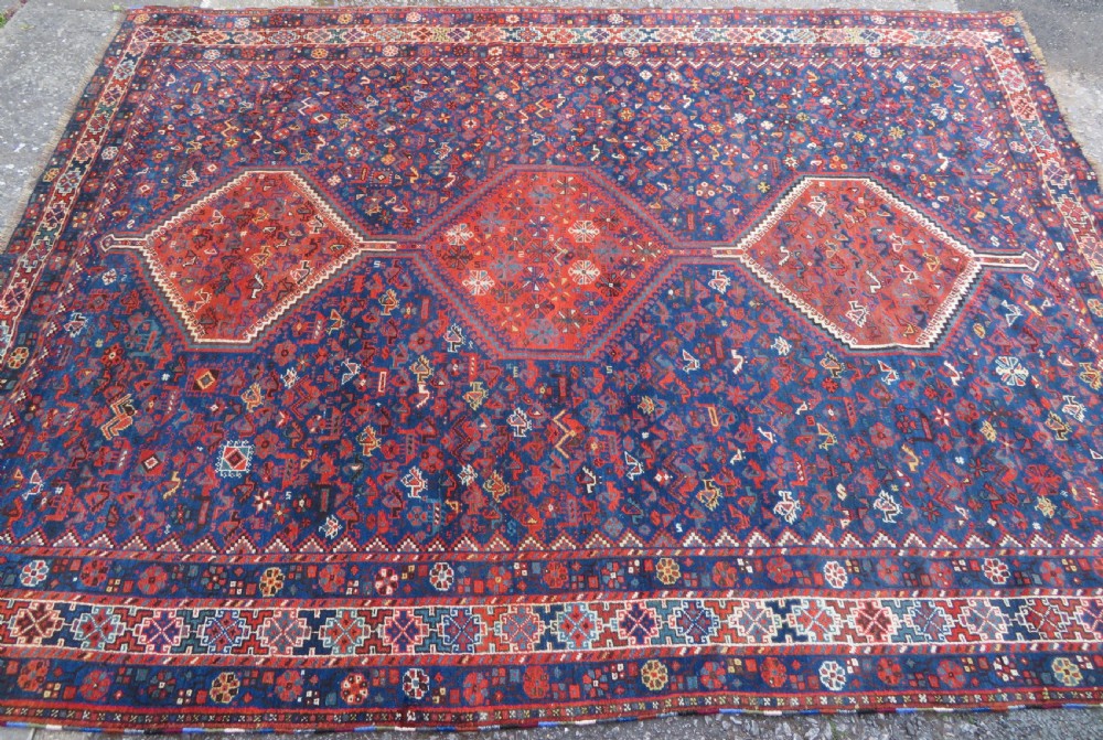 An antique Persian Khamseh carpet featuring three diamond-shaped central medallions and small bird motifs on a dark navy blue field with geometric borders. View III