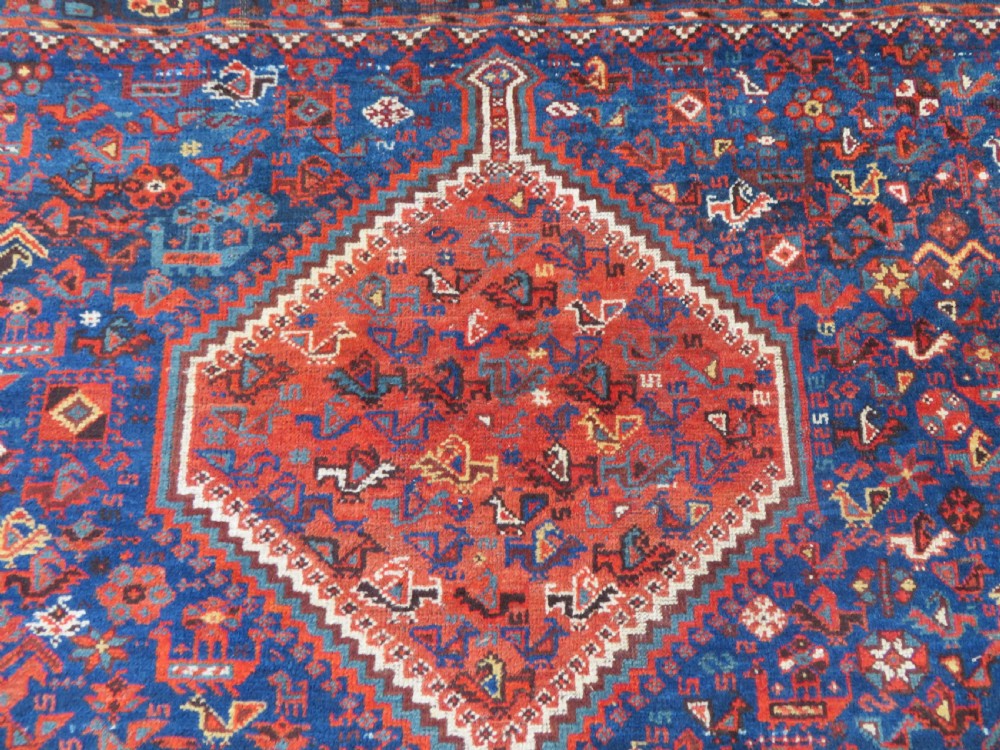 An antique Persian Khamseh carpet featuring three diamond-shaped central medallions and small bird motifs on a dark navy blue field with geometric borders. View V