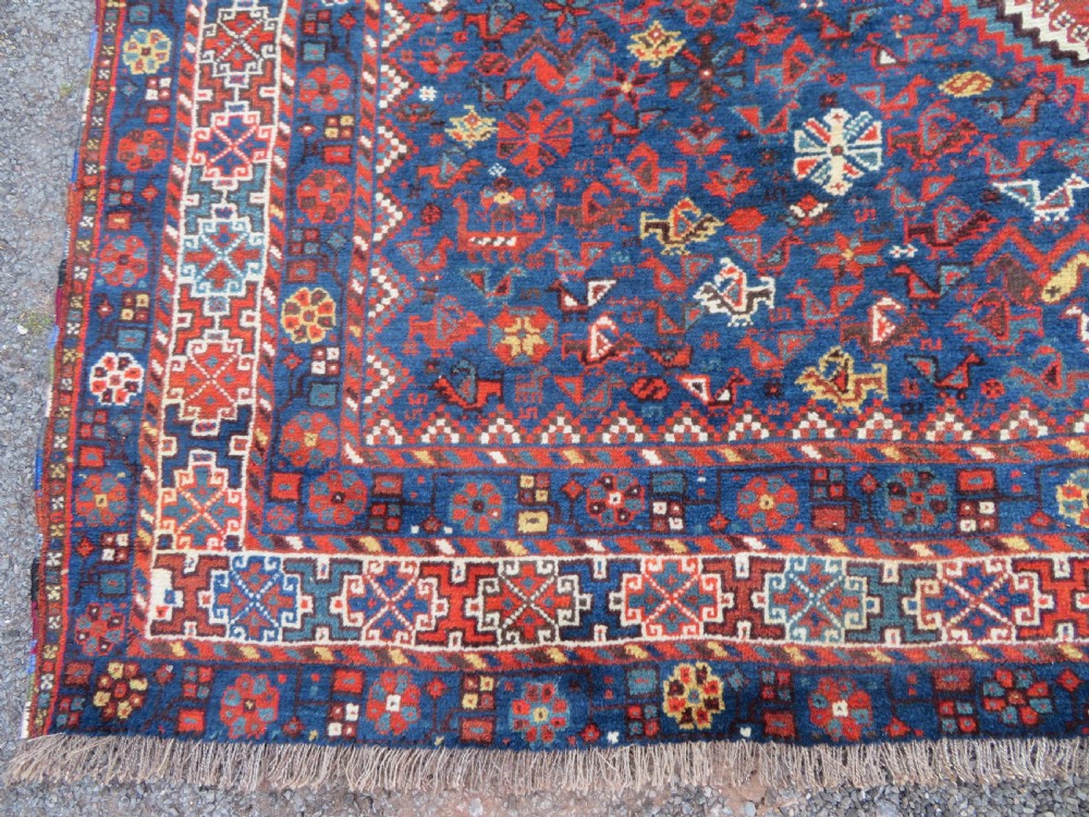 An antique Persian Khamseh carpet featuring three diamond-shaped central medallions and small bird motifs on a dark navy blue field with geometric borders. View XVI