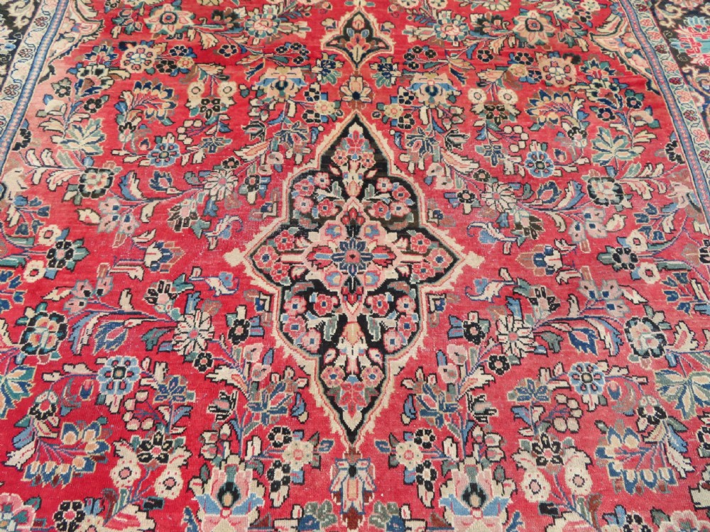 A large hand-knotted Sarouk Persian carpet featuring a dense red floral ground, central medallion, and elaborate dark borders. View IV