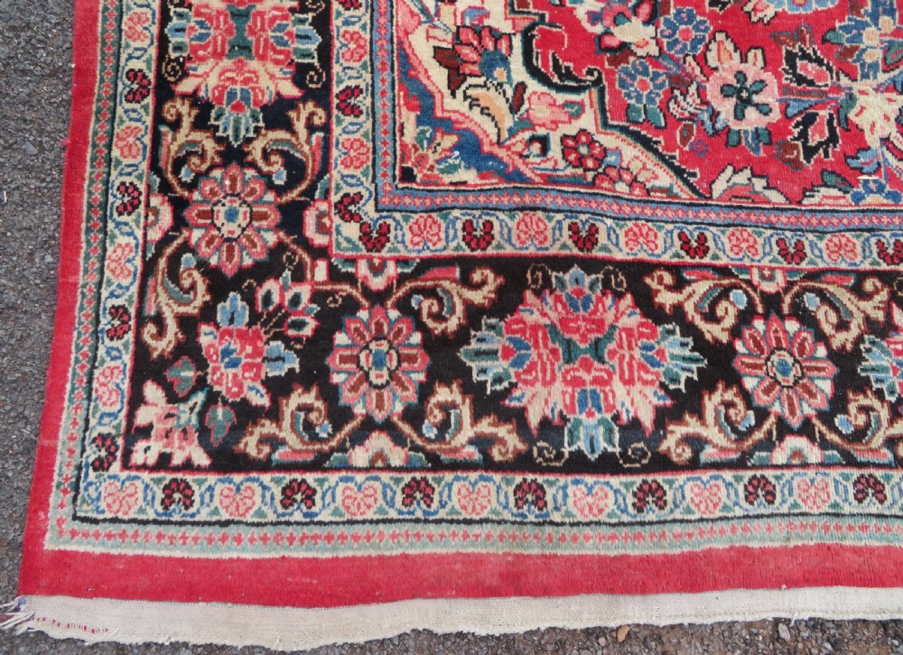 A large hand-knotted Sarouk Persian carpet featuring a dense red floral ground, central medallion, and elaborate dark borders. View VIII